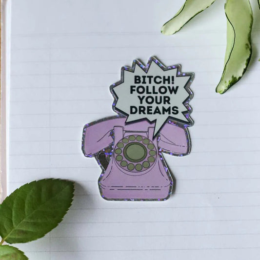 Puhelinan glittertarra tekstillä "Bitch follow your dreams" 